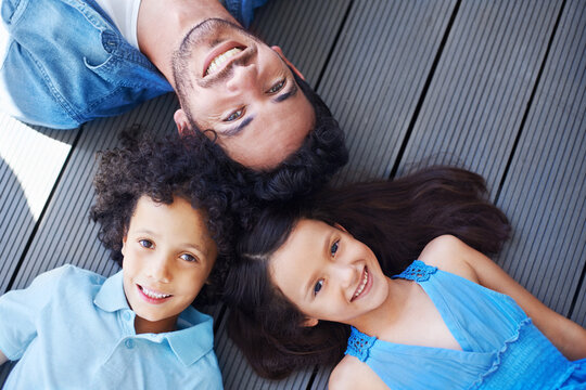 Theyre a close-knit family. High angle shot of a family lying on the floor and smiling up at the camera.