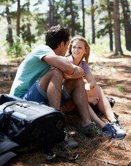 Enjoying some time outdoors. A happy young couple having a rest while on a hike in the forest.