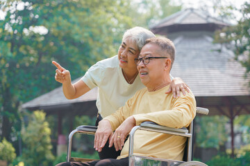 Senior couple and disabled husband in wheelchair to relaxation with watching nature view in park