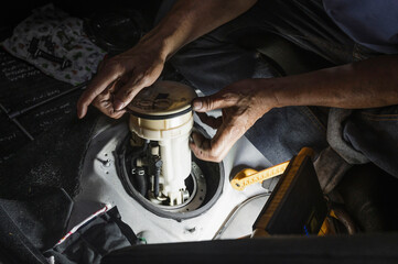 Auto mechanic checking car electric fuel pump module.