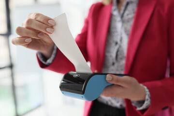 Secretary holds terminal in hand tearing off paper check