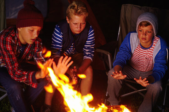 Lets hope there arent any bears out there...three young boys sitting by the campfire.