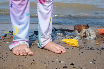 a girl is playing on the beach which is dirty because of garbage