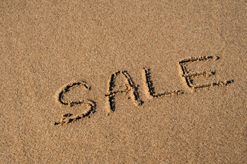 Text SALE handwritten in sand surface. Concept of promotion Black Friday Blue ocean wave washing away message at the beach. Summer holidays beach writing vacation concept
