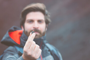 A young guy is holding a ladybug in the hand. A young guy is holding a ladybug in the hand. The face is out of focus. 