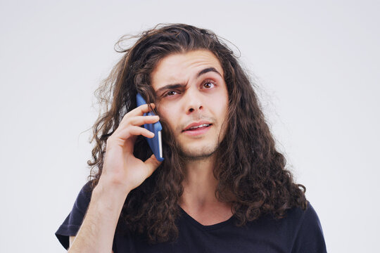 I Think You Have The Wrong Number. Studio Shot Of A Young Man Using A Mobile Phone Against A Grey Background.