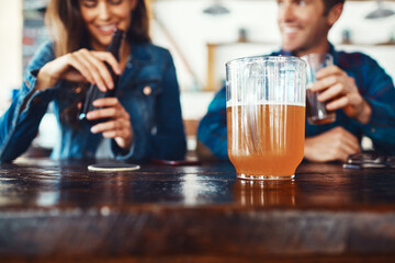 Cooling off with a glass or bottle. a young couple enjoying a drink at a bar.