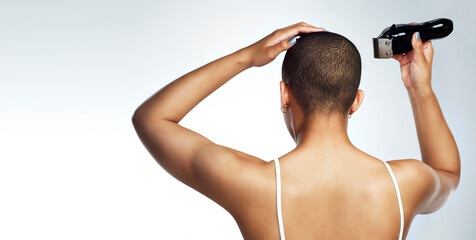 Let your story inspire others. Rearview shot of a young woman shaving her head against a white...