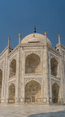 Fototapeta na wymiar Beautiful white marble Taj Mahal against the blue sky. The symmetrical mausoleum with arches, domes, spires is decorated with ornaments, inlays of precious stones. India. Agra