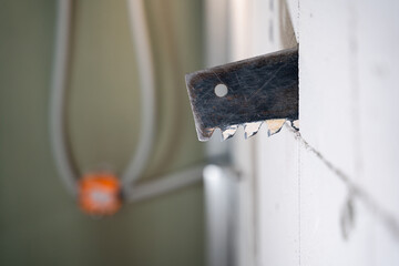 A hacksaw for aerated concrete sticks out of a wall of aerated concrete bricks close-up on a blurred background. Cutting a doorway in a gas block wall, handmade