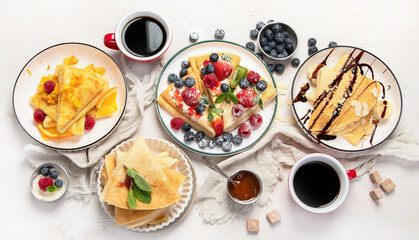 Sweet crepes assortment with berries chocolate on gray background. Homemade food concept. Top view, flat lay