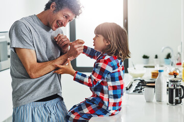 The tickle monster is coming for you. a mature father and his young son in the kitchen at home.