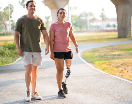 Exercise walking Asia woman with prosthetic leg and friend in the park	