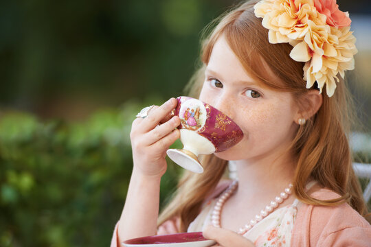 Sipping my tea...A young girl playing dress up and sipping from her tea cup in the garden.