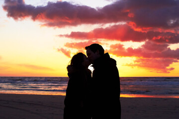 Beach, sunset and couple silhouette kiss in nature with love, freedom and romance outdoors. Shadow,...