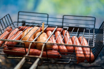 BBQ in the garden. Grilling sausages on barbecue grill.  Bavarian sausages. Barbecue cooking. Cooking food on an open fire.
