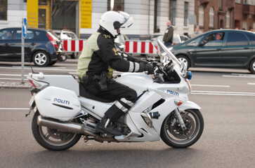 Police, motorbike and road safety officer working for protection and peace in an urban neighborhood in Denmark. Security, law and legal professional or policeman on a motorcycle ready for service