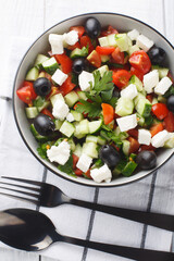 Turkish fresh vegetables Shepherd Salad closeup in the bowl on the wooden table. Vertical top view from above
