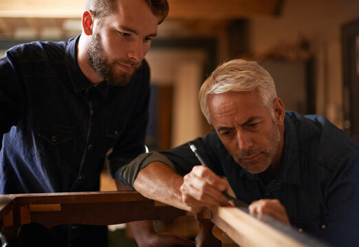 Teaching, learning and carpentry apprentice and help with pencil in designer furniture manufacturing workshop. Mentorship, carpenter and young man, wood and teamwork at sustainable business project.