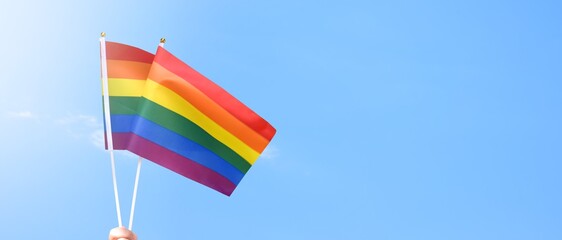 Rainbow flag raising against cloudy and bluesky background, copy space, concept for LGBT celebrations in pride month, June, around the world.