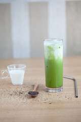 Iced Green matcha tea mixed with ice cube and milk in latte glass on white. Space for text. Close up.
