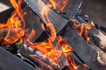 The firewood in the grill burns with a bright orange flame. Preparation for cooking meat on the...