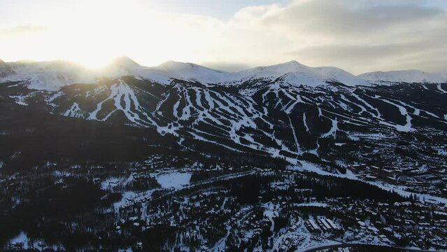 Aerial Cinematic drone view of Breckenridge Ski area and town from Boreas Pass late afternoon sunset over mountain tops mid winter pan forward reveal movement