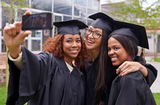 Education, women celebrating graduation with selfie and group at the ceremony outside on campus. University or college academic achievement, female students take photo and people dressed in cloaks