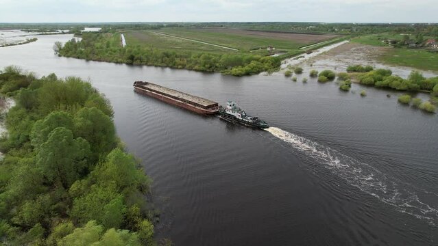 The pusher tug pushes the barge down the river. Pripyat River, Belarus.