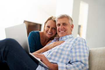 Time to get comfy and connect. Portrait of a mature couple using a laptop together at home.