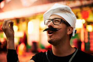 Its manifique. a young man dressed up as a chef at an outdoor festival.