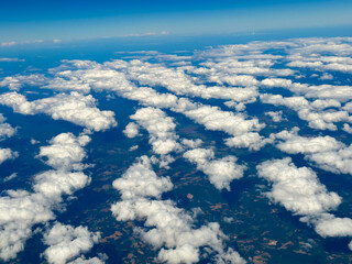 Naklejka premium Sunrise above clouds from airplane window. fluffy white clouds with blue background.