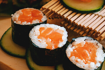 Salmon Sushi Rolls with Avocado - A close-up of delicious salmon sushi rolls placed on avocado slices, featuring extra avocado and bamboo presentation.