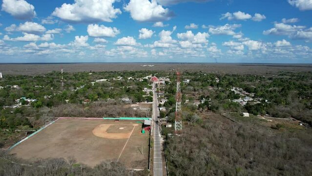 backwards aerial shot of church and baseball campo at tahmek yucatan mexico