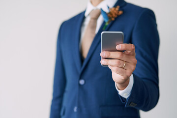 Relationship status update Married. Cropped studio shot of a stylish groom using a mobile phone against a gray background.