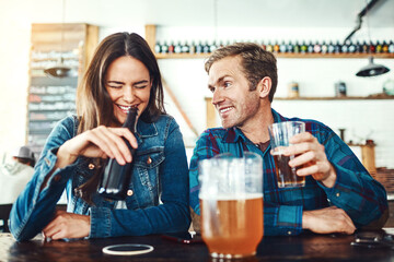 He loves that he makes her laugh. a young couple enjoying a drink at a bar.