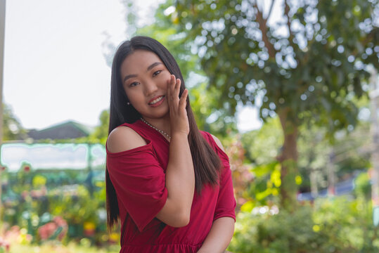 A close- up image of a lovely Asian woman tells a secret or whispers a gossip by hiding her mouth to the opposite side