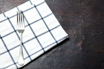 Kitchen table with towel and fork. Wooden table with a cloth napkin. Above view with copy space, place for text