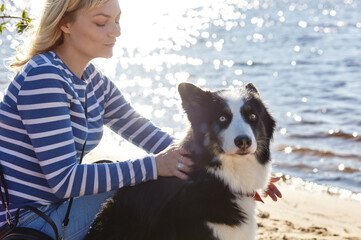 Owner with a siberian laika dog on a beach. Friendship of a dog and a woman