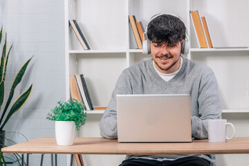 young man at home studying online with headphones and laptop