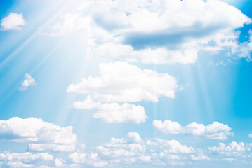 Blue sky background with tiny clouds and sunbeams.