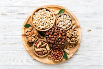 mixed nuts in wooden bowl. Mix of various nuts on colored background. pistachios, cashews, walnuts, hazelnuts, peanuts and brazil nuts
