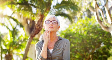 Whats your advice to your younger self. a senior woman looking thoughtful at the park.