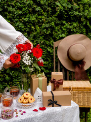Gift box and flowers in hands against spring background. Family holiday concept. Mothers day