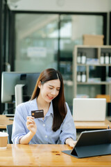 Asian Woman using smart phone for mobile payments online shopping,omni channel,sitting on table,virtual icons graphics interface screen in morning light.