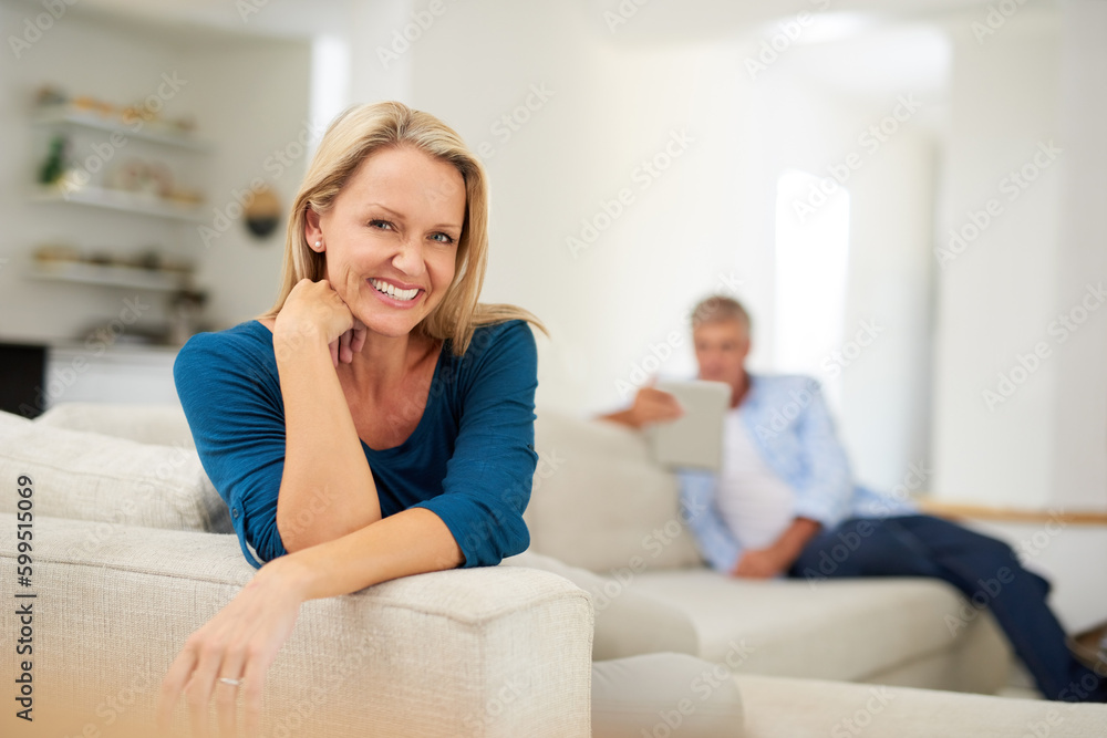 Poster Cosy and comfortable weekends are what theyre all about. Portrait of a mature woman relaxing at home with her husband in the background.