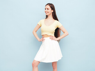 Image portrait of optimistic woman in yellow  t-shirt and white skirt. Carefree stylish model with long hair. Smiling female posing in studio. Isolated. Looks delightful and cute. Slim