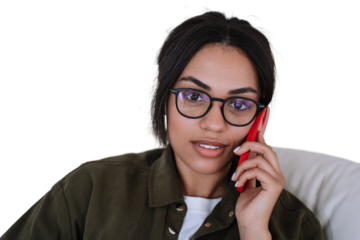 Confident Beautiful Brazilian young woman in glasses talking by phone looking at camera. Pretty African American female against transparent background received using cell phone. Business people
