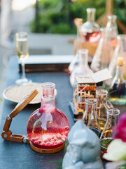 Decorated party. Flasks and test tubes with cocktails. Flask with wooden magnifier, pink cocktail.