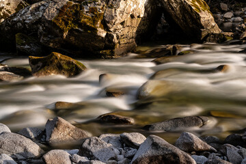 Torrente di montagna in luce diurna fotografato con esposizione lunga, effetto mosso dell'acqua che scorre velocemente